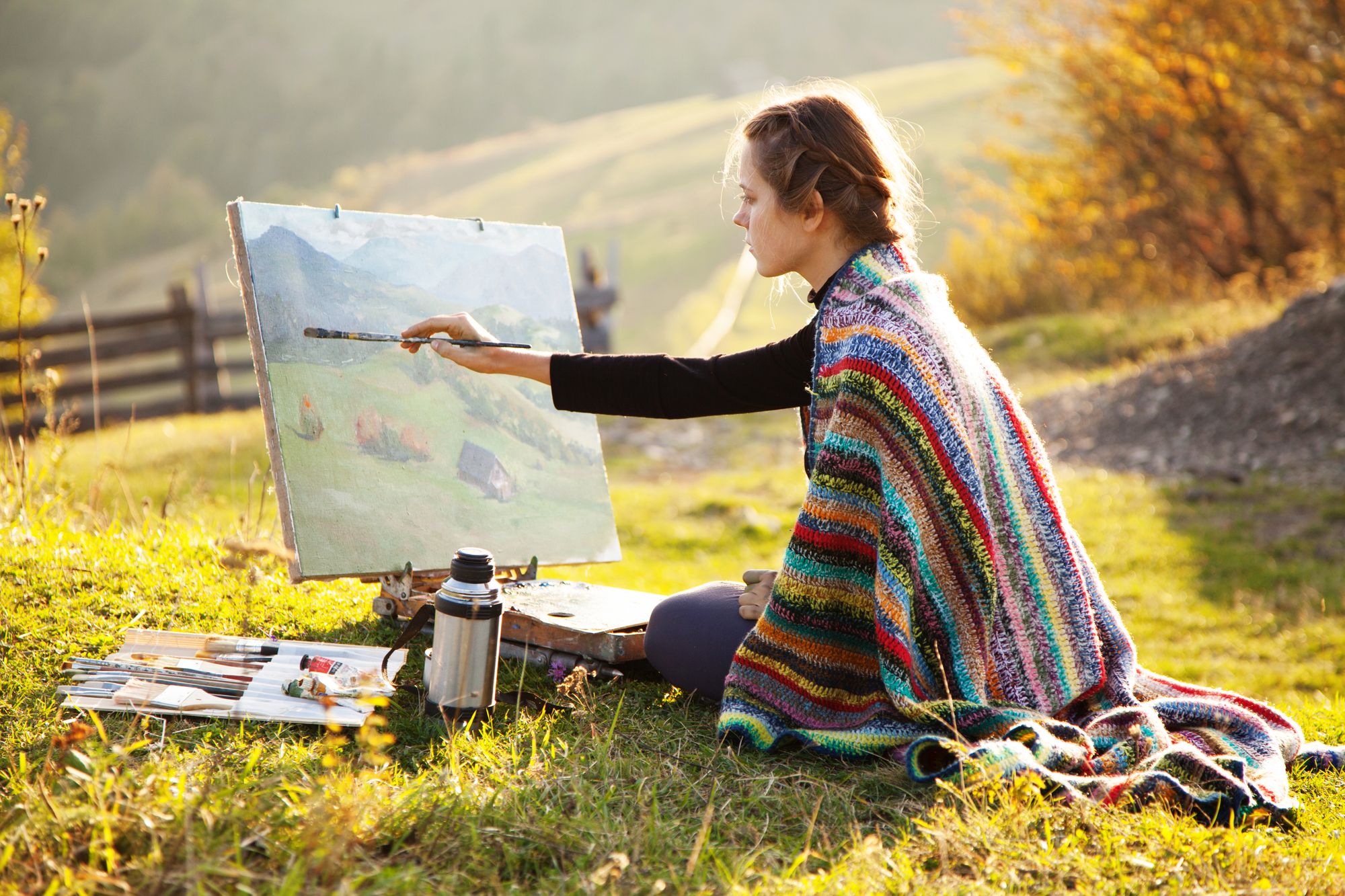 A woman painting a beautiful landscape outdoors