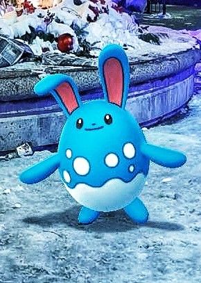 A blue pokemon that looks like a bunny, called Azumarill. It's standing on the snow, with a water fountain behind it.