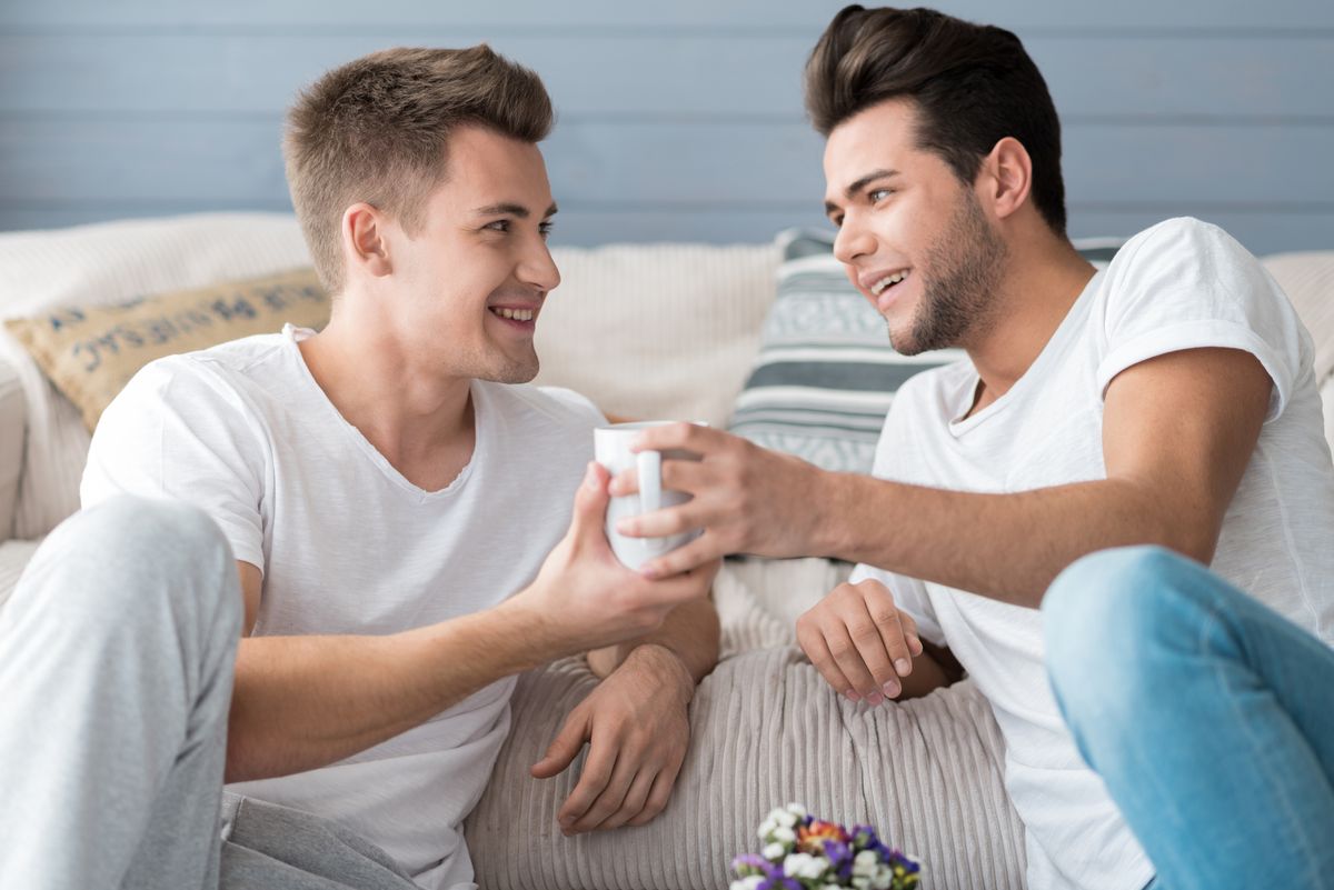 Two men smiling and holding a cup together