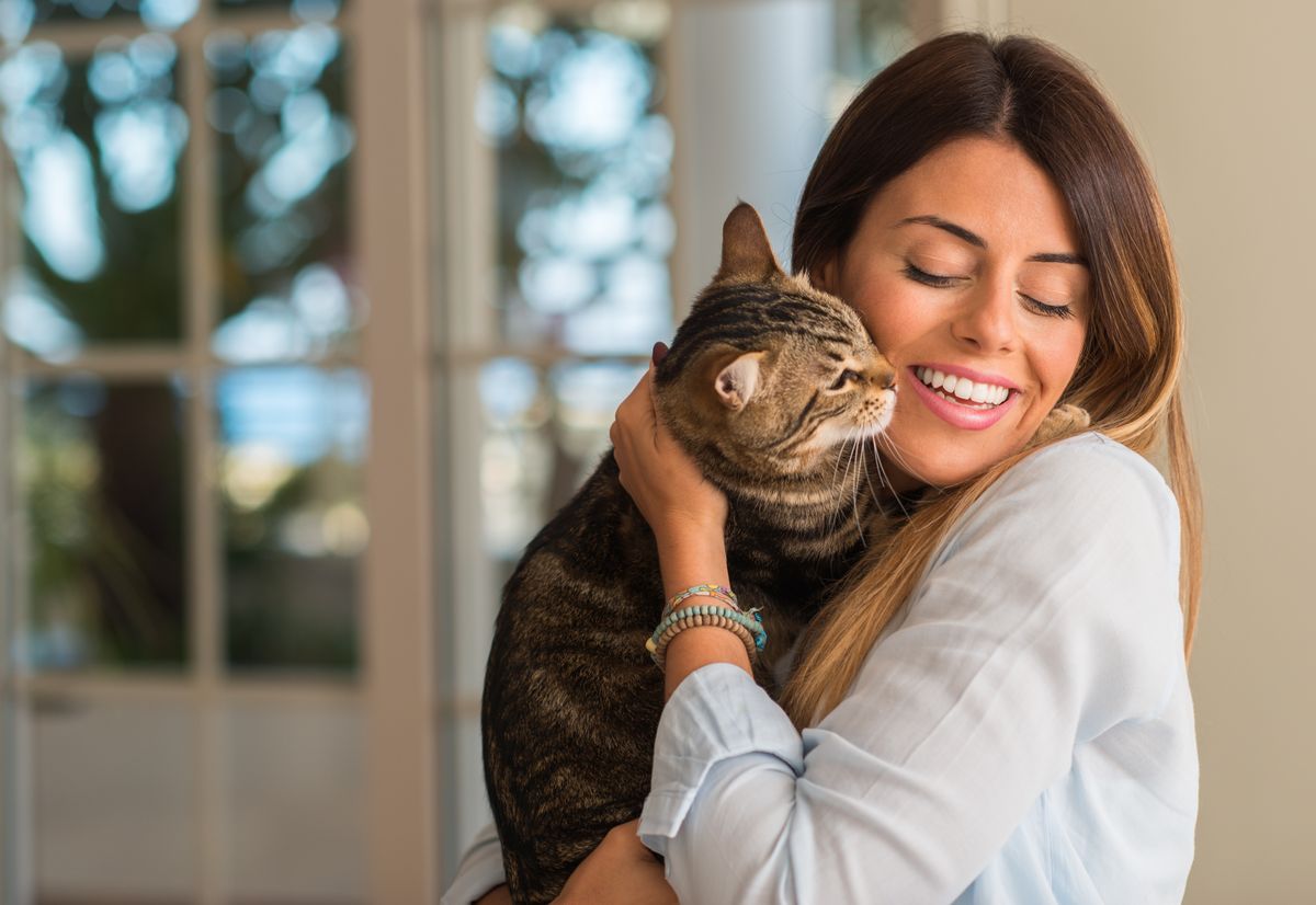 A smiling woman hugging her cute cat.