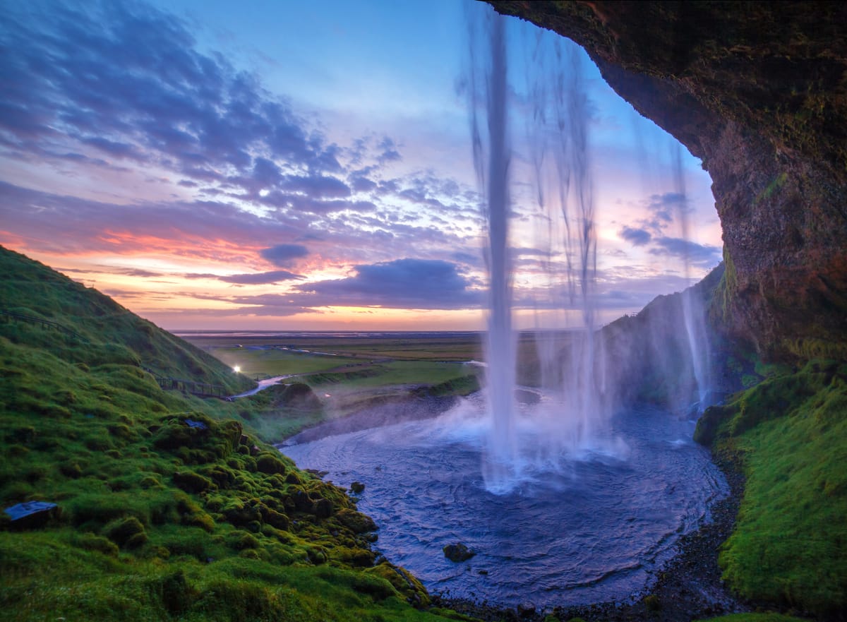 A majestic waterfall crashing into a pool, with a beautiful sunset in the background.