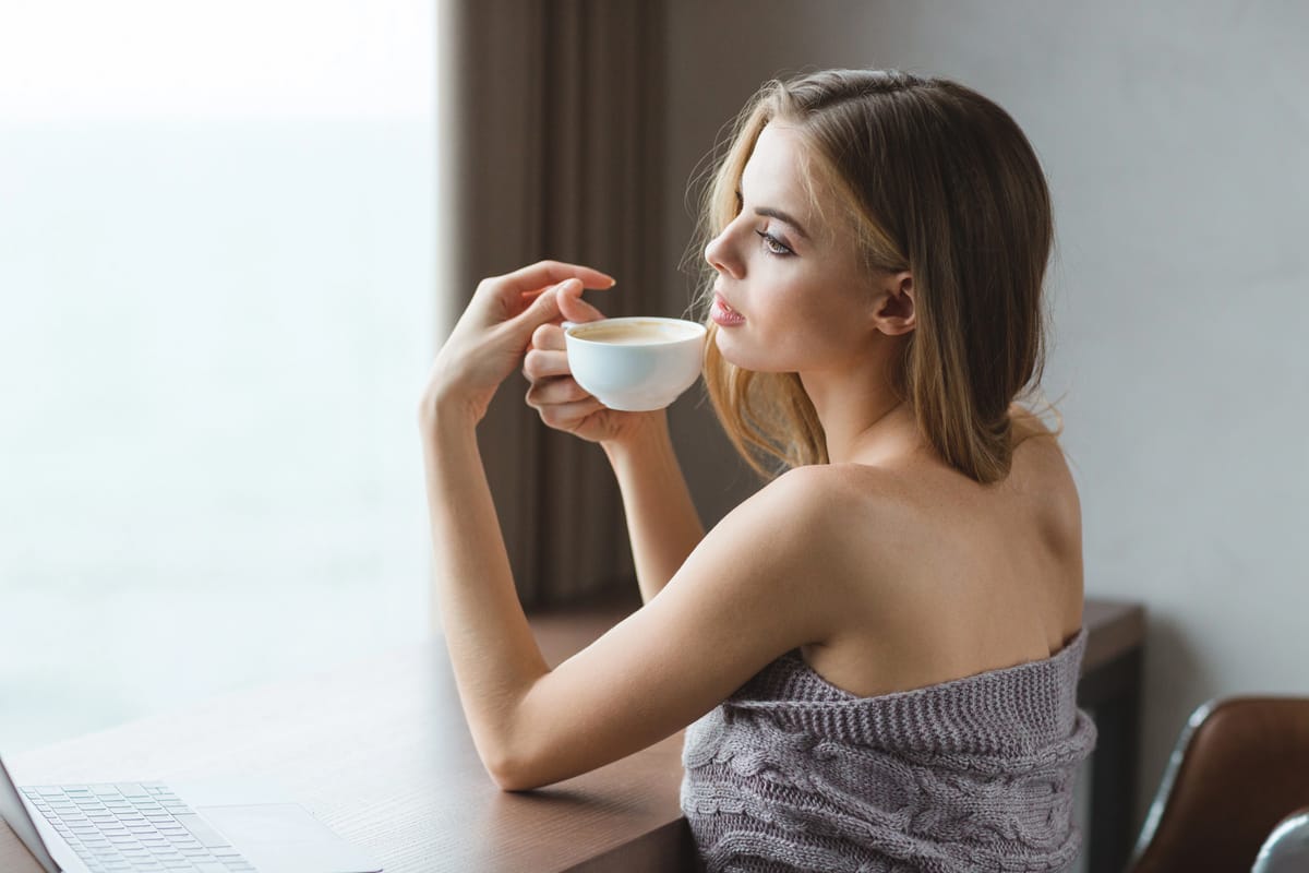 A beautiful girl enjoys coffee while beside her laptop